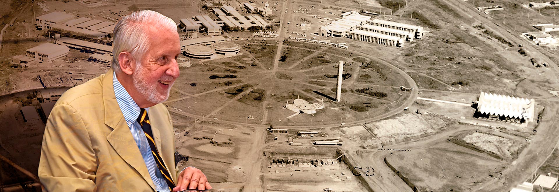 Composição com duas fotos. À esquerda aparece um homem de lado, do peito para cima. Ele é branco, tem cabelos brancos, usa terno bege e está sorrindo. Ao fundo aparece uma foto aérea de um terreno com prédios em construção