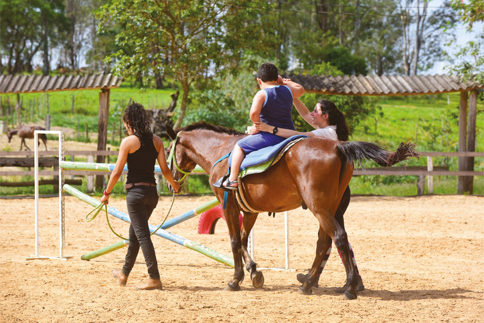 Criança com Transtorno do Espectro Autista durante sessão de equoterapia em Barão Geraldo, distrito de Campinas: cavalo desempenha função de agente terapêutico transformador