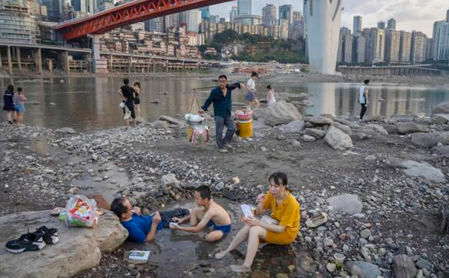 Pessoas sentadas em uma piscina rasa de água no leito do rio Jialing, um afluente do Yangtze, no município de Chongqing, no sudoeste da China