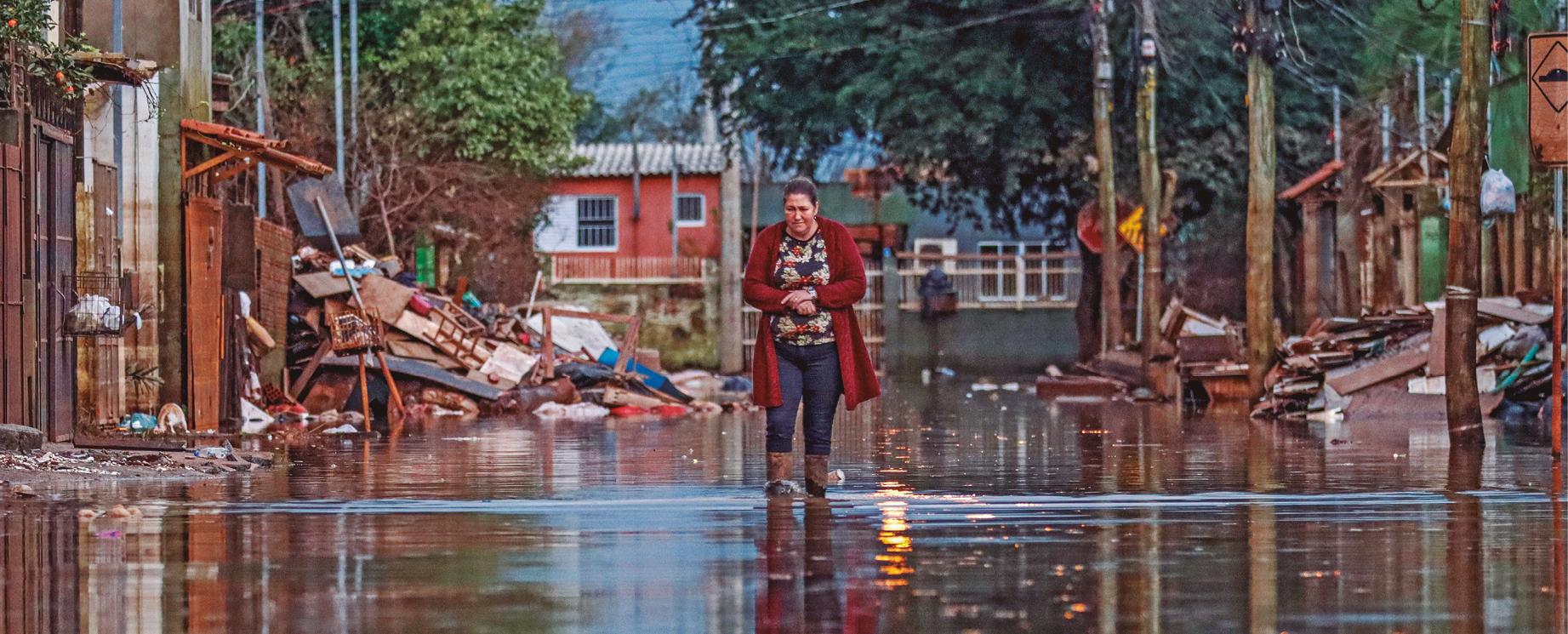 Moradora caminha por rua alagada na Vila da Paz, bairro de Porto Alegre, depois das chuvas que atingiram a capital gaúcha e a maior parte do Estado em junho deste ano 