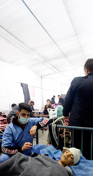 Imagem mostra um médico diante atendendo um paciente ferido